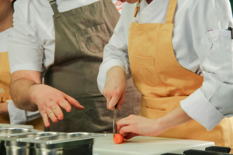 Close-up of chefs chopping carrots in a modern kitchen setting.
